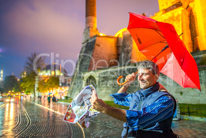 Tourist male with map and umbrella in front of Hagia Sophia, Ist