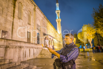 Tourist with map in front of Instanbul Blue Mosque at night