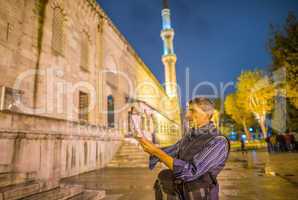 Tourist with map in front of Instanbul Blue Mosque at night
