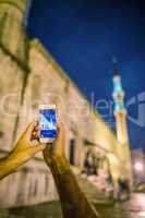 Tourist photographing Blue Mosque with smartphone at night, Ista