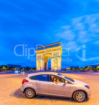 Car with mother and daughter in front of Triumph Arc at night in