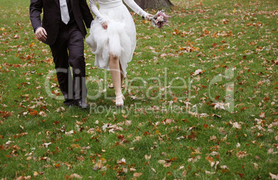 Bride and groom running on grass