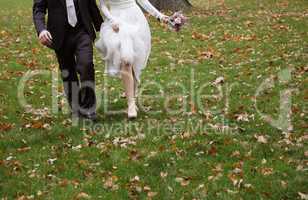 Bride and groom running on grass