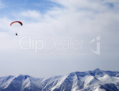 Paraglider silhouette of mountains in sunlight sky