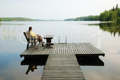 Lake with wooden platform and woman resting.