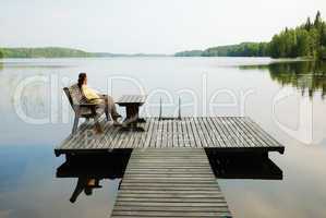 Lake with wooden platform and woman resting.