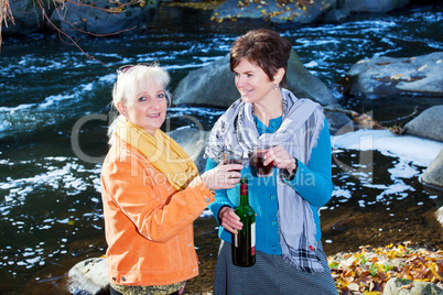 Two women enjoying leisure time on the river with wine