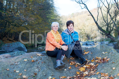 Two women sitting on a rock in the river
