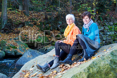 Two women sitting on a rock in the river