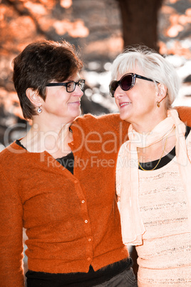 Two middle-aged women hugging in nature