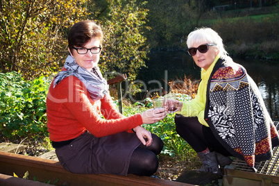 Two women with a glass of red wine in nature