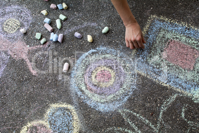 Woman paints with colored chalk on asphalt - Stock Image