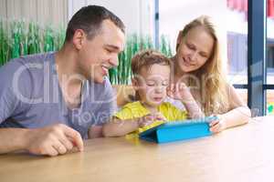 Happy family of three with tablet computer in cafe