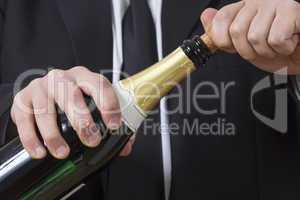 Man in siut opening Champagne bottle