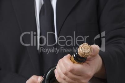 Man in siut opening Champagne bottle