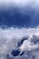 Snowy mountains in clouds and sunlight sky