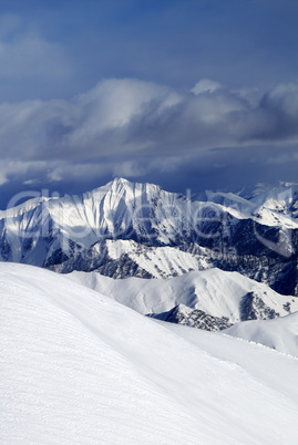 Off-piste snowy slope and cloudy mountains