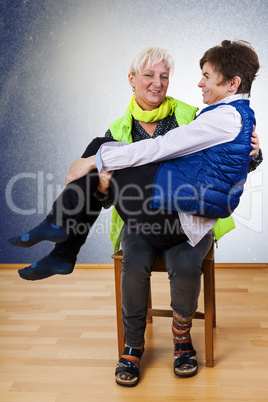 Seated woman holding another woman for fun