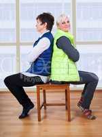 Two women sitting back to back on the chair