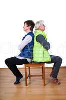 Two women sitting back to back on the chair