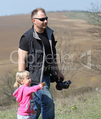 Father and her daughter playing in the nature with a toy car