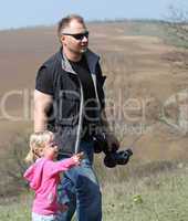 Father and her daughter playing in the nature with a toy car