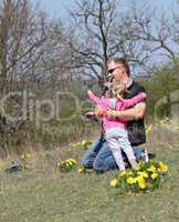 Father and her daughter playing in the nature with a toy car