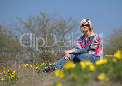 Young beautiful woman sitting in blooming garden