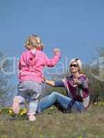 Mother and her running daughter relaxing in the nature with yellow flowers