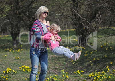 Mother and daughter spinning in a park with yellow flowers