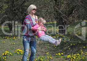 Mother and daughter spinning in a park with yellow flowers