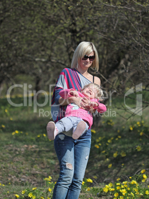 Mother and daughter spinning in a park with yellow flowers