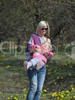 Mother and daughter spinning in a park with yellow flowers