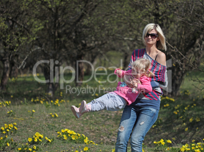 Mother and daughter spinning in a park with yellow flowers