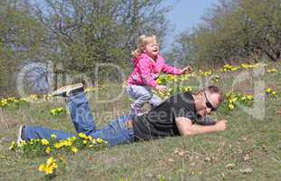 A man with a young blonde daughter playing in the  nature