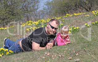 Father and daughter lying outdoors with flowers