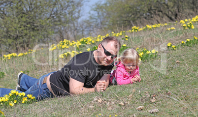 Father and daughter lying outdoors with flowers