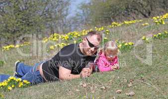 Father and daughter lying outdoors with flowers