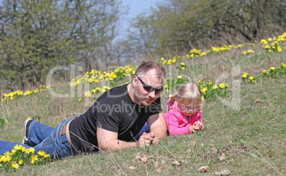 Father and daughter lying outdoors with flowers