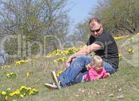 Father and daughter lying outdoors with flowers