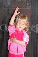 Little girl wearing pink standing and holds hands up