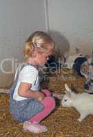 Happy girl with blond hair playing with rabbits