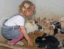 Happy girl with blond hair playing with rabbits