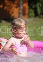 Little blonde girl playing in a water-filled kiddie pool