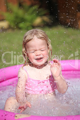 Little blonde girl playing in a water-filled kiddie pool