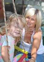 Smiling mother and daughter having fun on playground