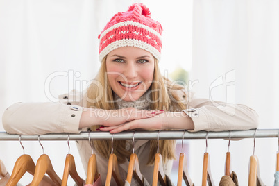 Pretty blonde smiling at camera by clothes rail