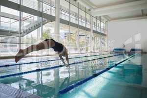 Fit swimmer diving into the pool at leisure center