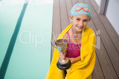 Cute little girl sitting poolside wrapped in towel