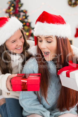 Festive mother and daughter exchanging gifts